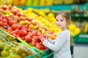 Young girl in fruit section of supermarket